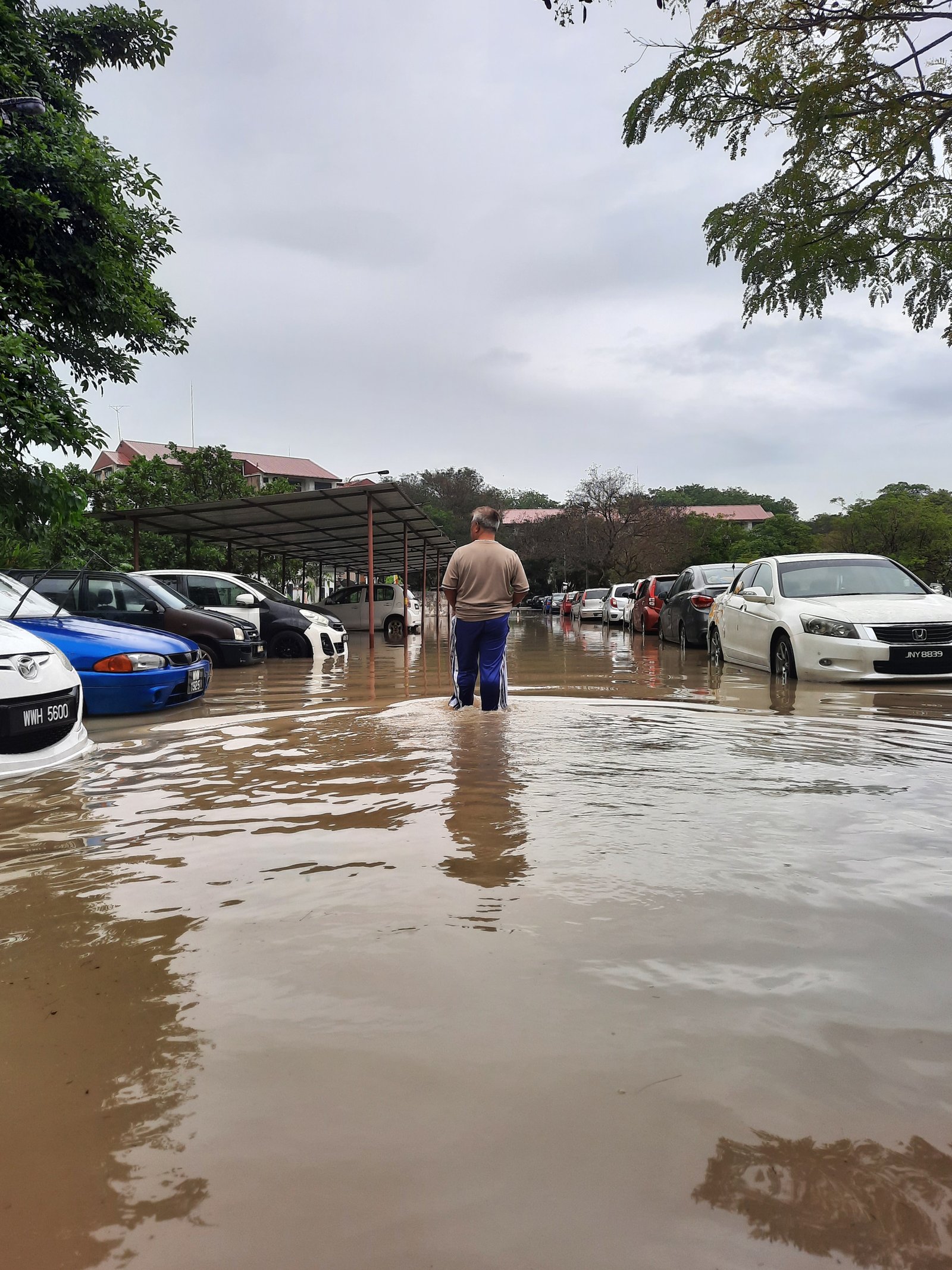 A man walking through knee-deep floodwater in a residential car park in Section 24, Shah Alam, during the December 2021 Malaysian floods